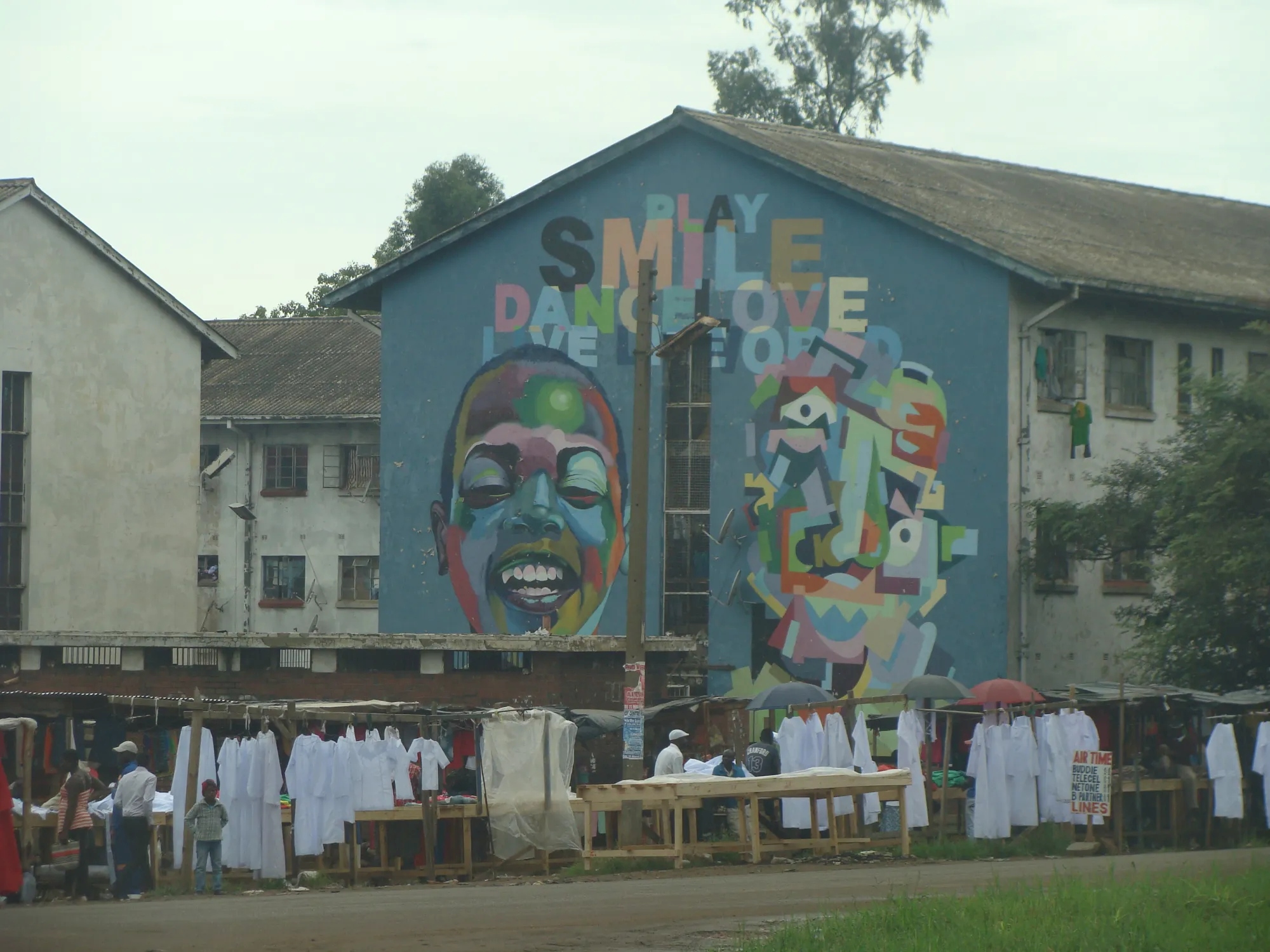 Colorful mural on the side of a bulding depicting a smiling face 