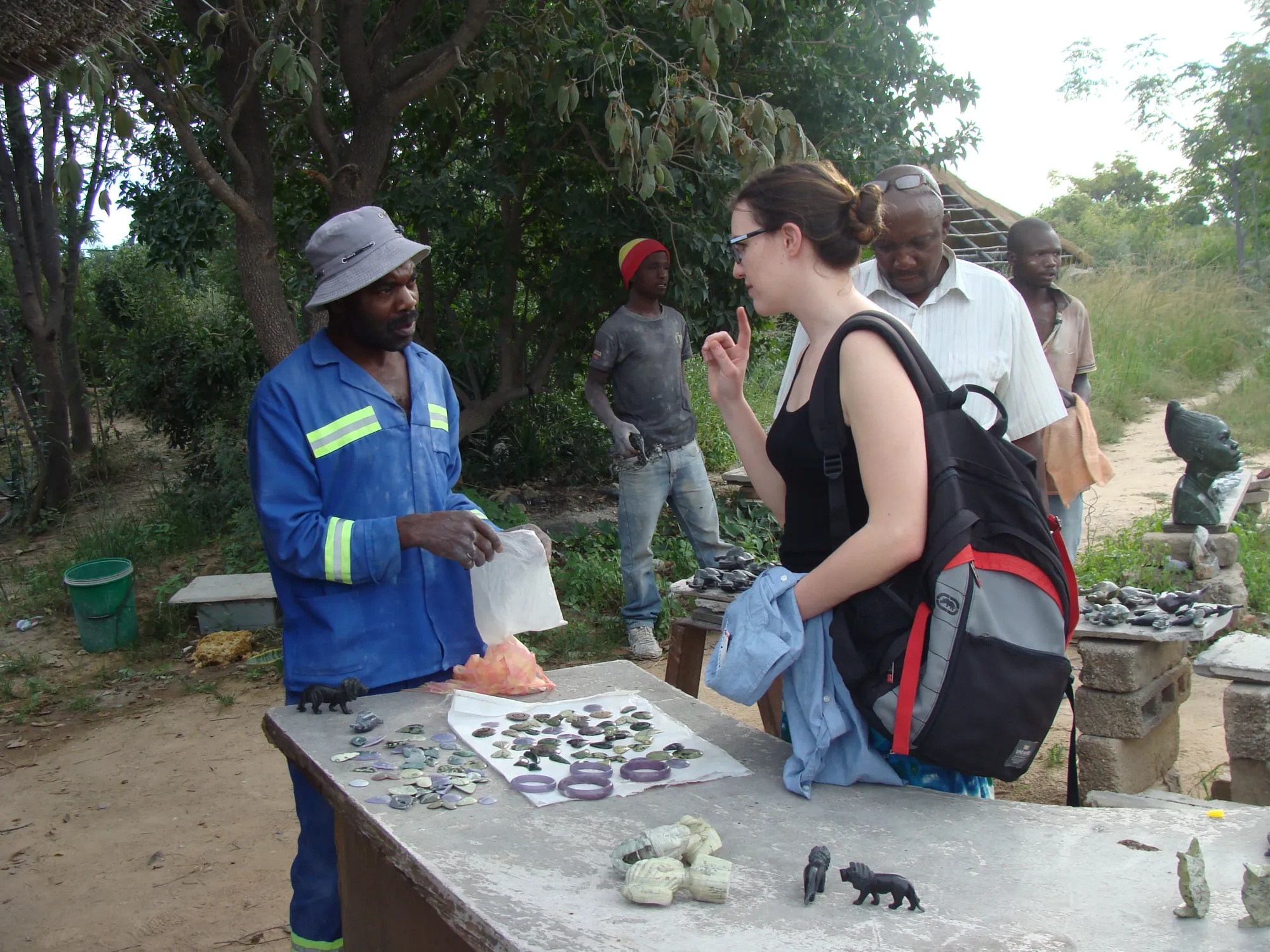 Woman bargaining with an artist in an outdoor artisan space, he is selling bangals