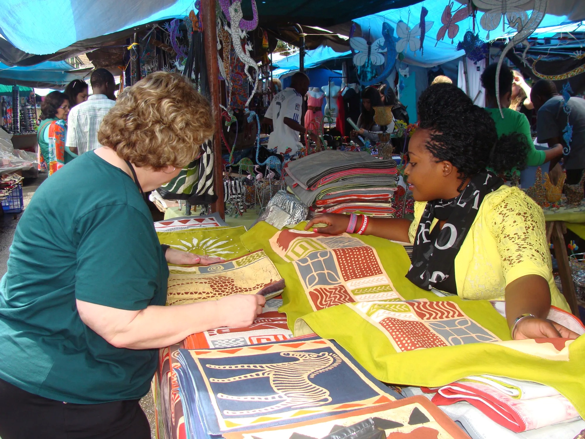 Woamn bargaining with a vendor over some textiles 
