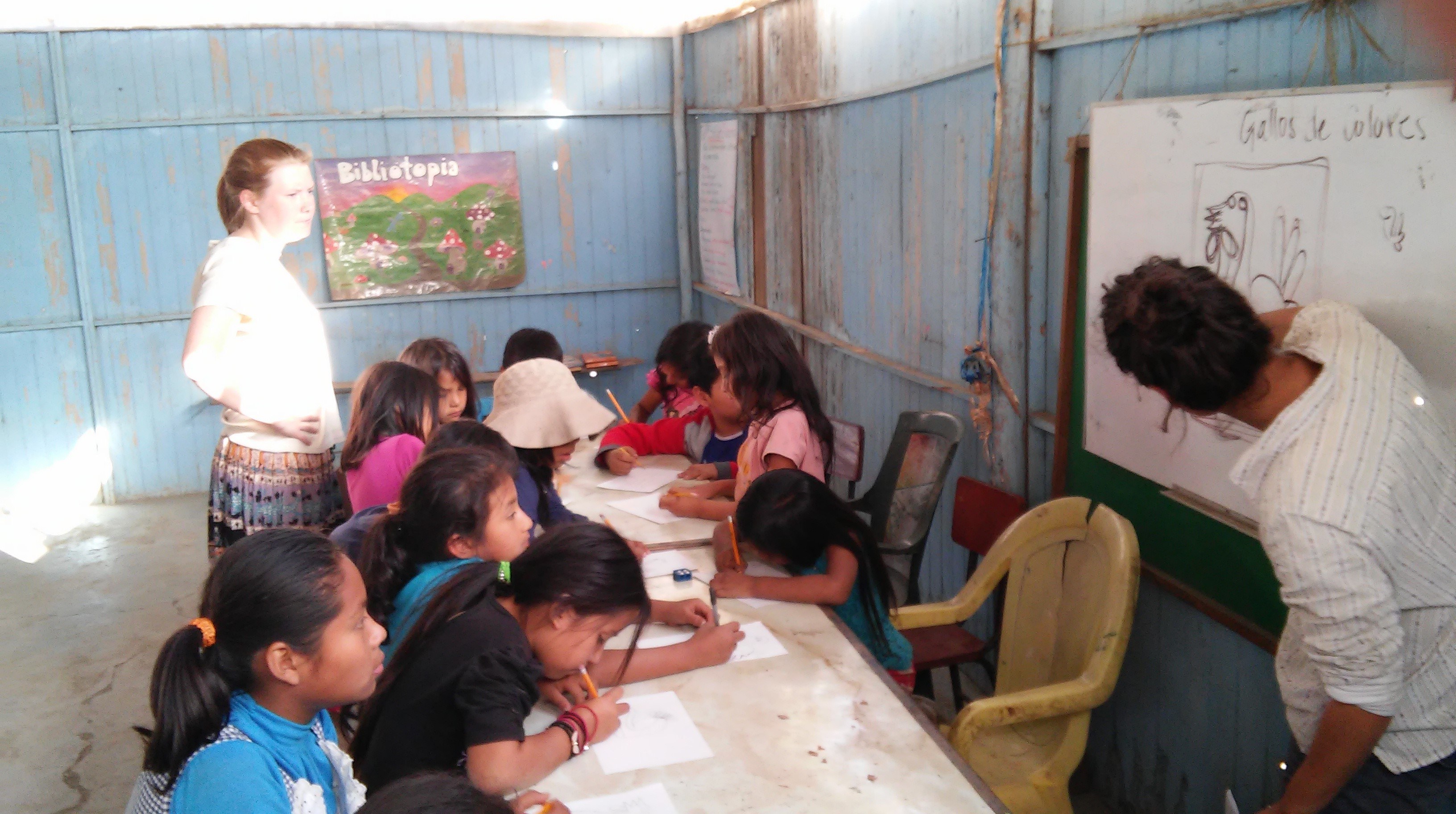 Adult volunteer helping young children in an art class