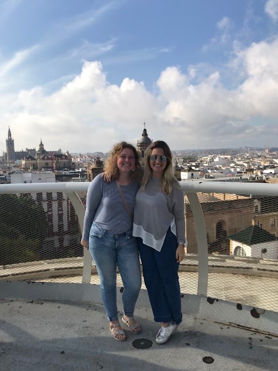 Two young women standing on a balcony with Sevilla, Spain in the background