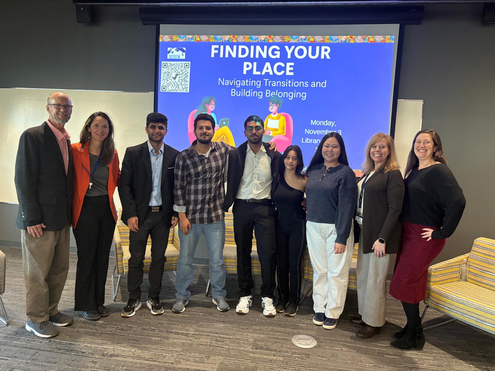 students smiling for a picture in front of the Find Your Place display