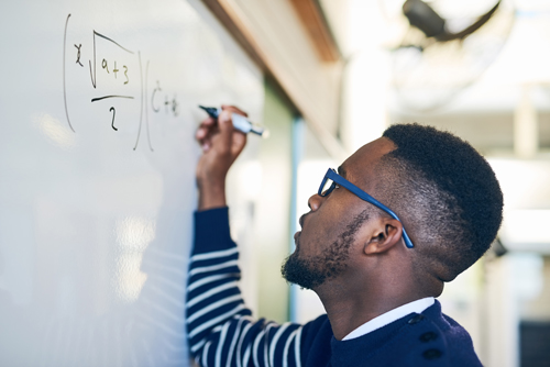 man writing math equations on white board