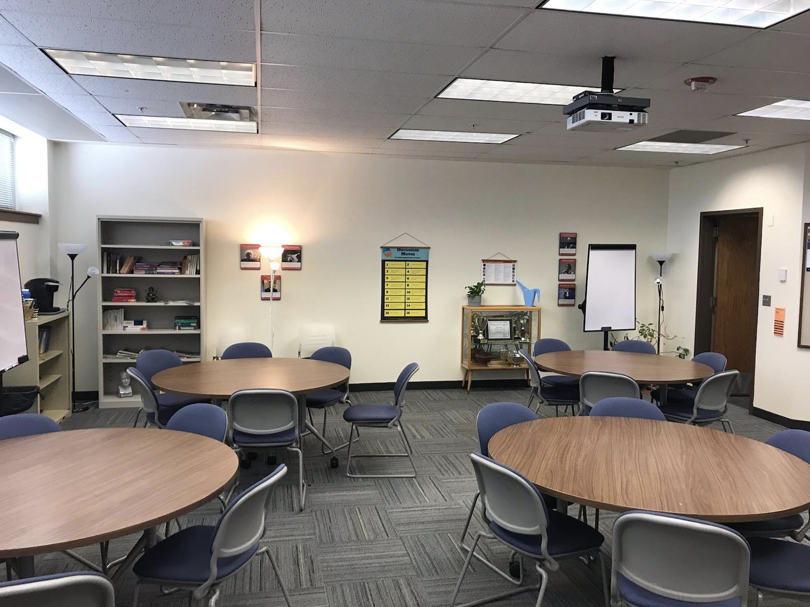 Harper's Philosophy Learning Labs Photo of the Philosophy Learning Labs featuring round tables surrounded chairs, quotes from philsophers on the walls, and a trophy case chowcasing the various awards won by Harper's Ethics Bowl team.