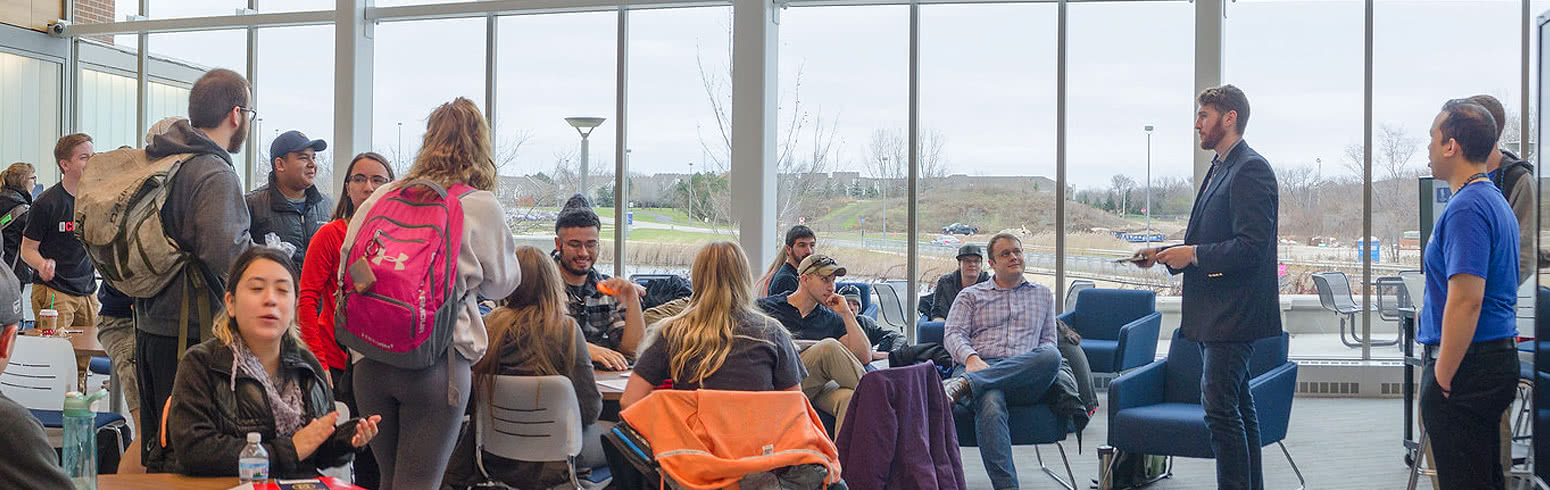 Professor talks to students in common area.