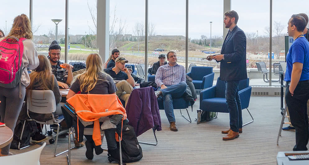 Professor talks to students in common area.