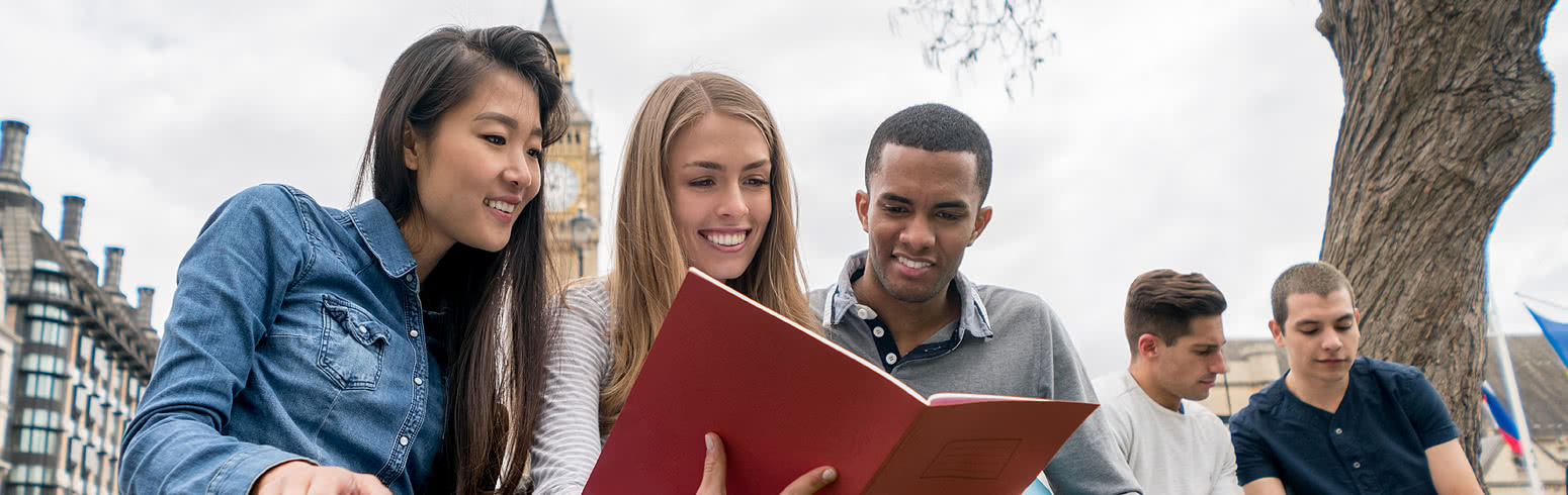 Students reading a book together. Big Ben is in the background.