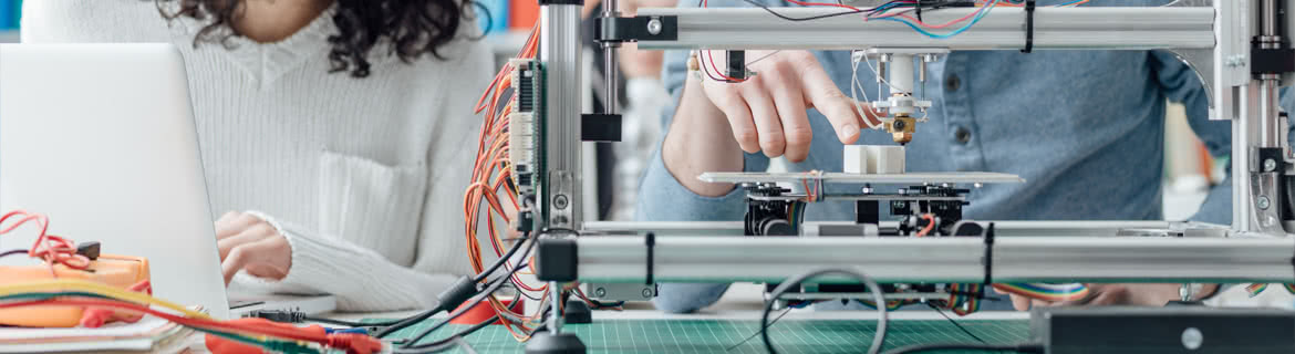 A pair of manufacturing students working on a machine and recording the results.