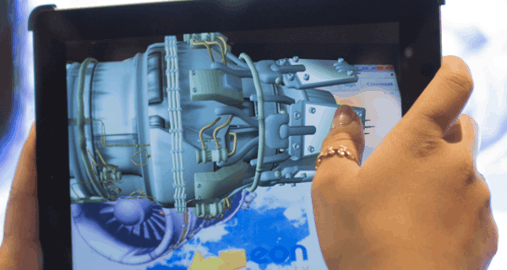 Hands holding a tablet displaying a 3D model of an engine part.
