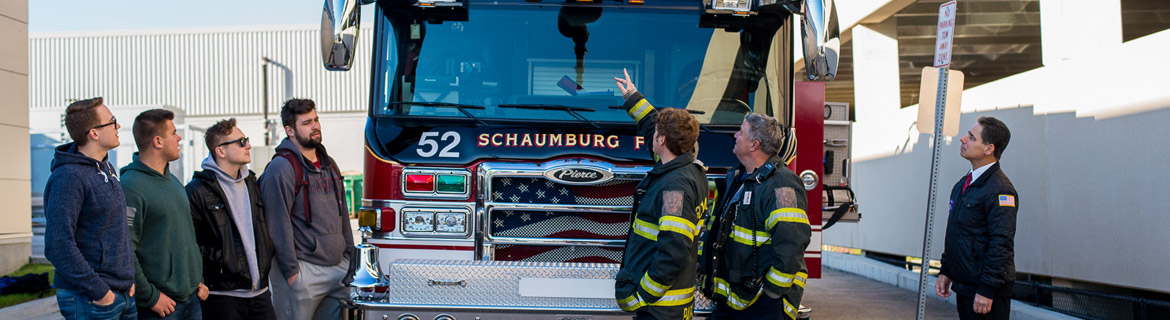 Firefighters lead a tour of a fire truck for fire science students.