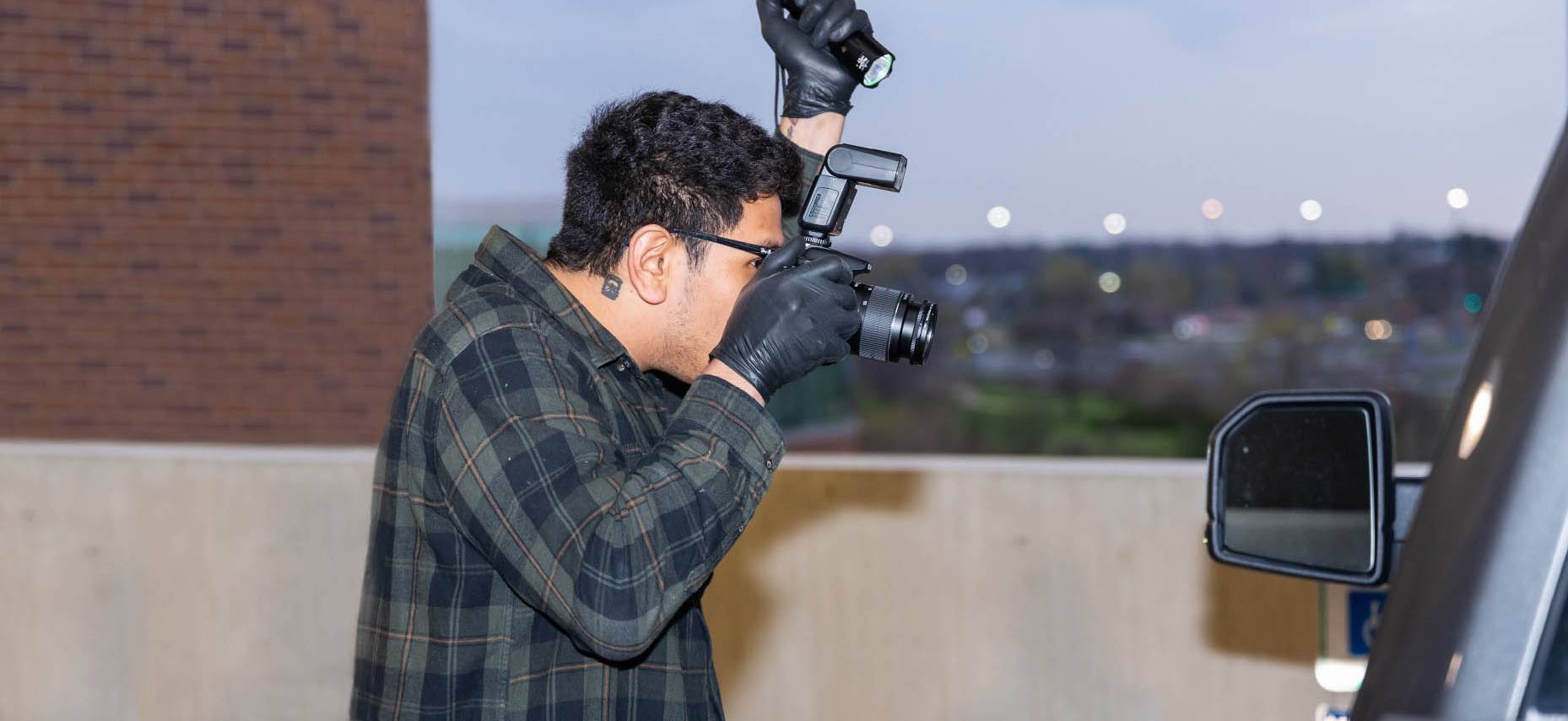 Student pursuing an associate degree in Forensic Science at Harper College takes a photo of a mock crime scene on campus in the Chicago suburbs.