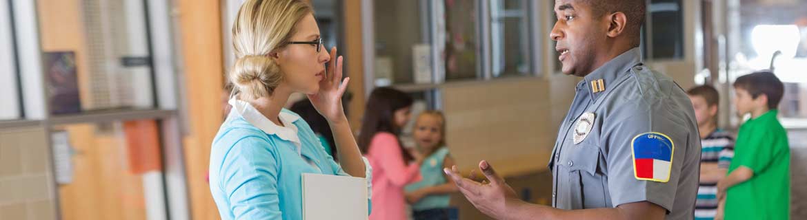 Law enforcement individual conversing with teacher