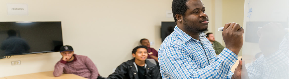 A student writes on a whiteboard in a classroom.