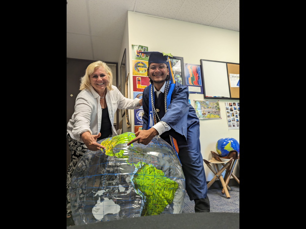 Geography professor Veronica Mormino and a Harper College graduate point at an inflatable globe.