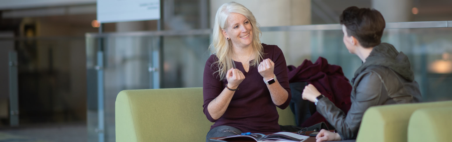 Women converse in sign language in building lobby.