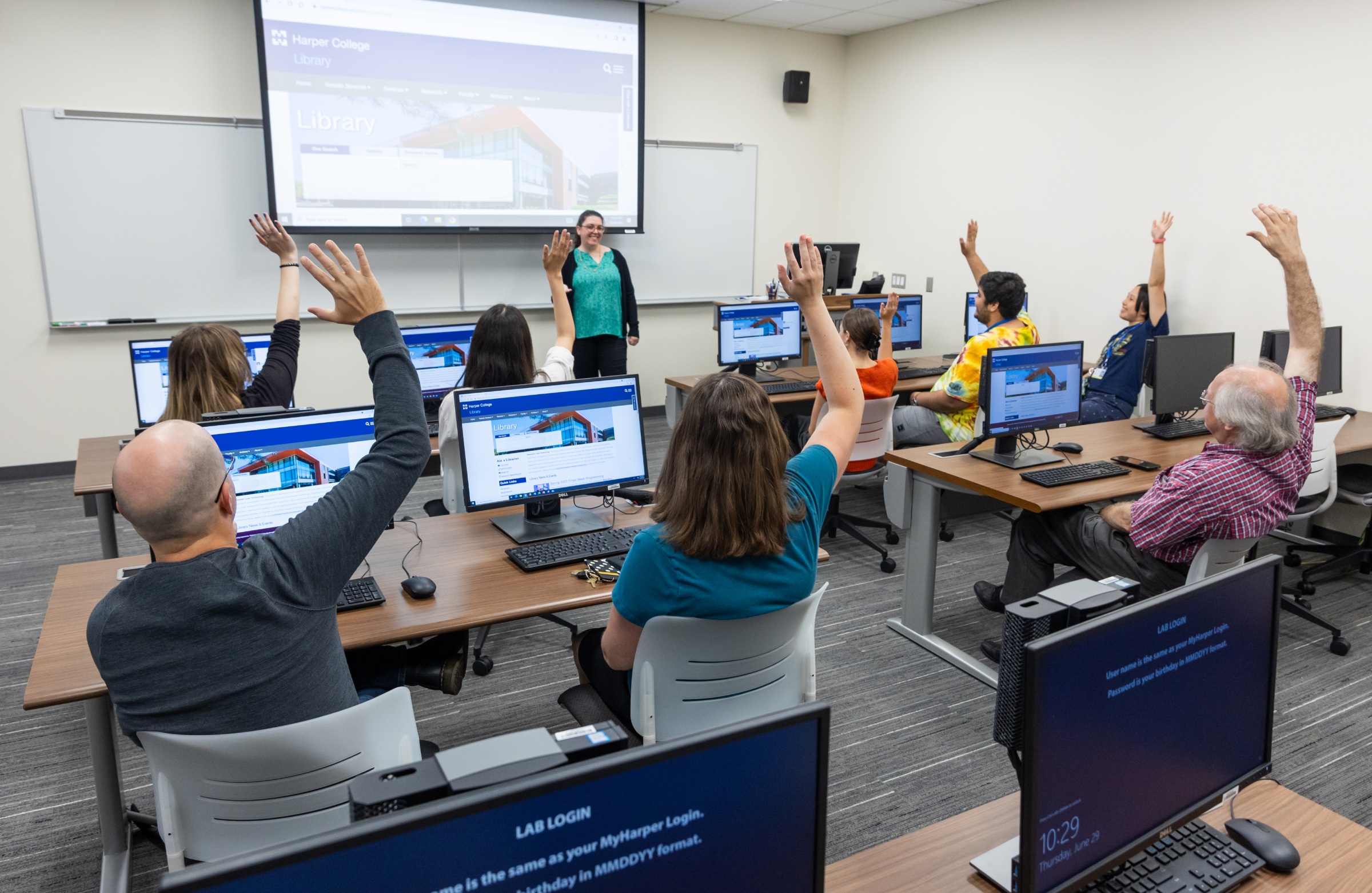 Students raising their hands to answer a question in a classroom on the Harper College campus in Palatine, Ilinois.