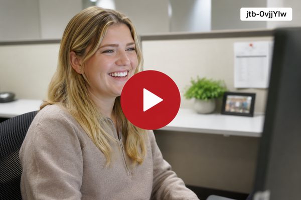 Sydney smiles while working at a computer in a professional office setting.