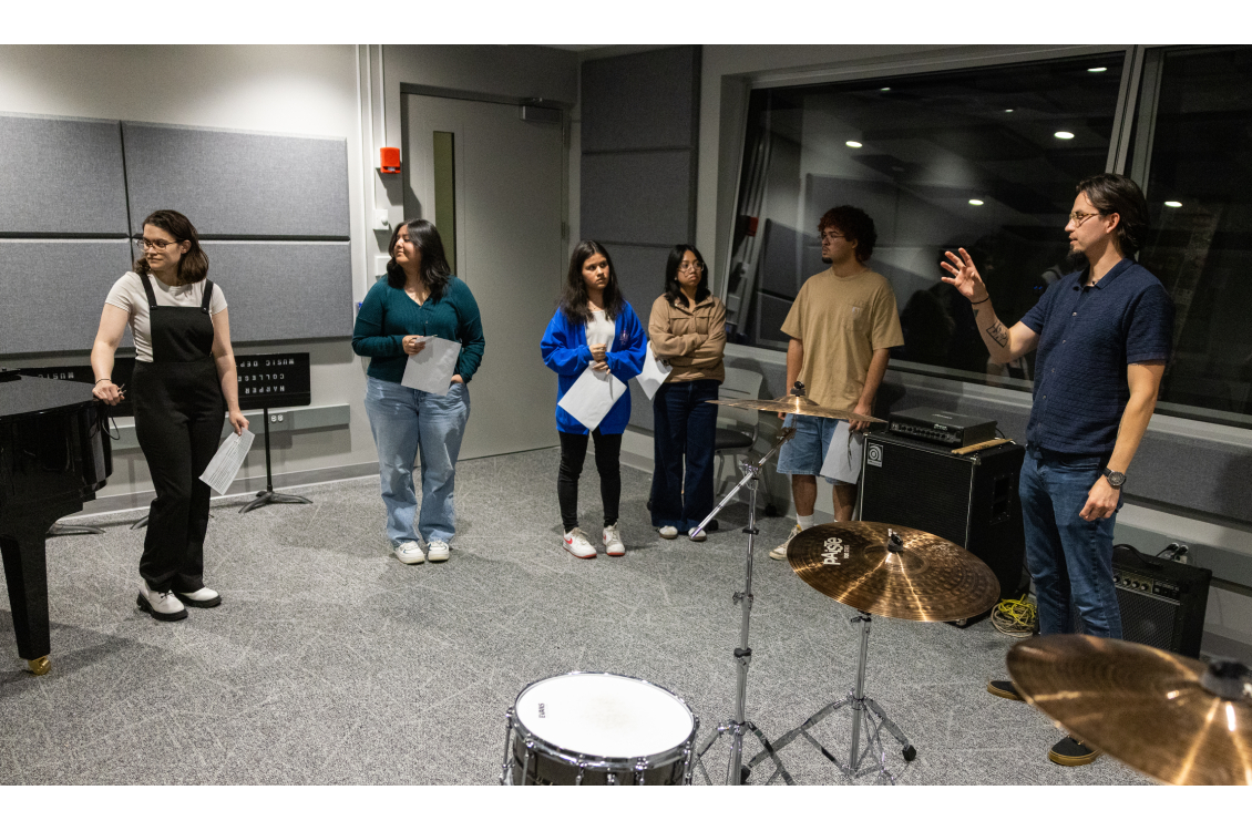 Music students stand in the recording booth and listen to an explanation about the technology
