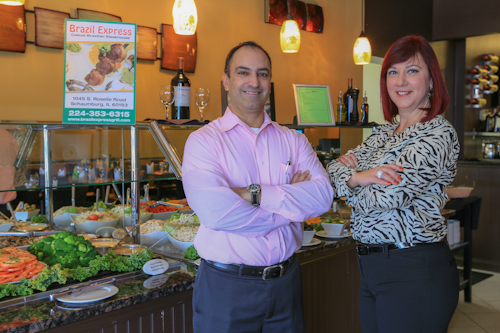 Front-facing picture of Ana Santos-Vitelo and her husband standing in their restaurant, Brazil Express Churrasco Grill. 