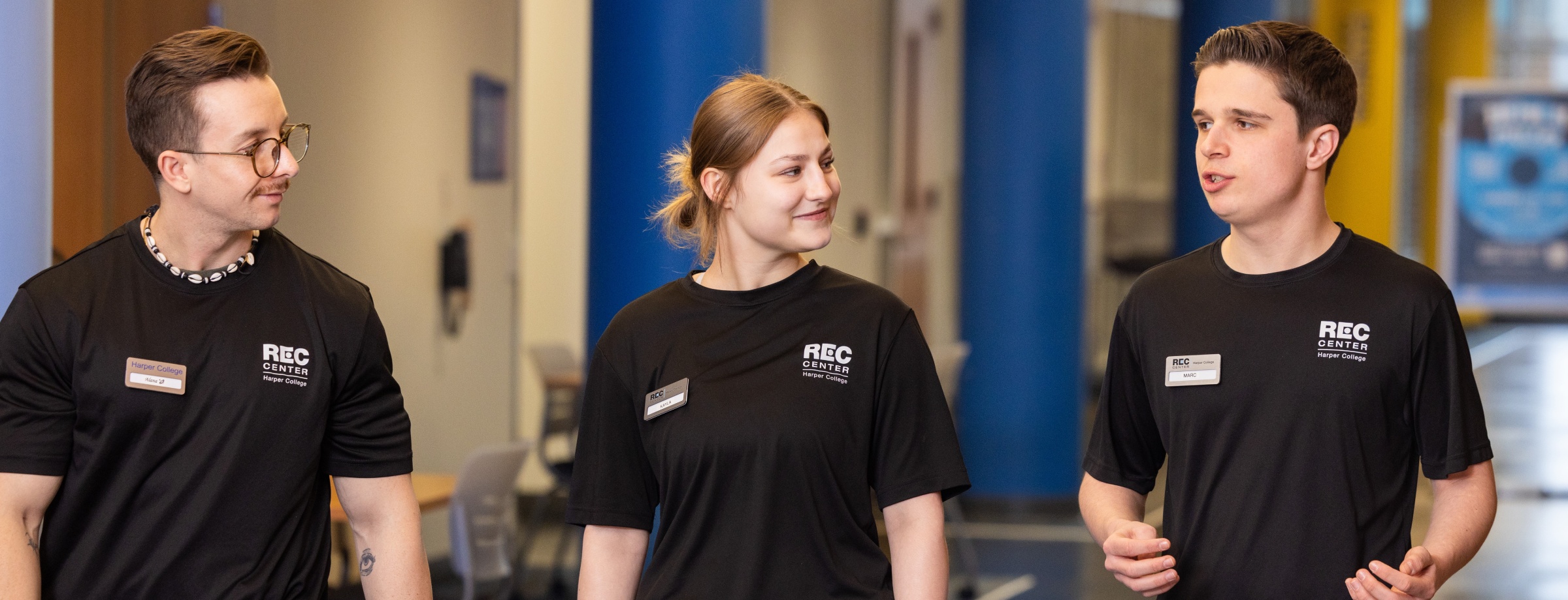 Three Harper College Rec Center employees walking together through Building M.