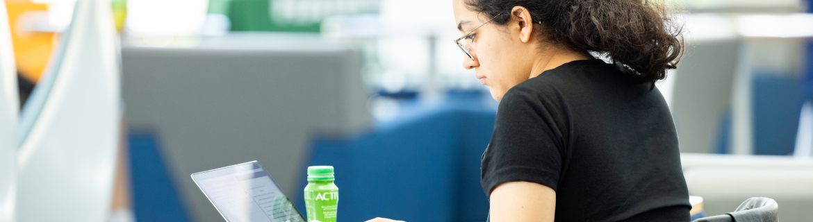 a harper college student studying at a table with a laptop