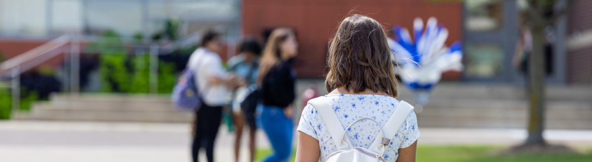 a Harper College student with a backpack walking across the quad on campus