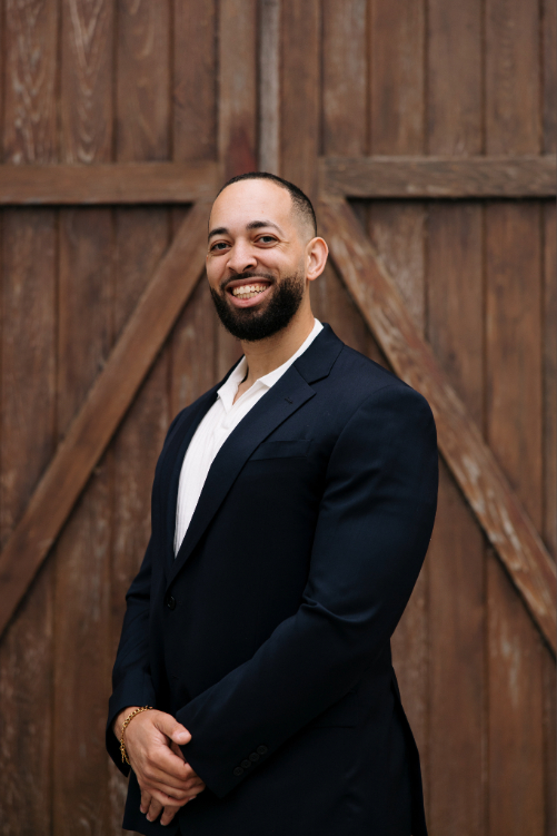 Isaiah Carrington stands with hands crossed, smiling