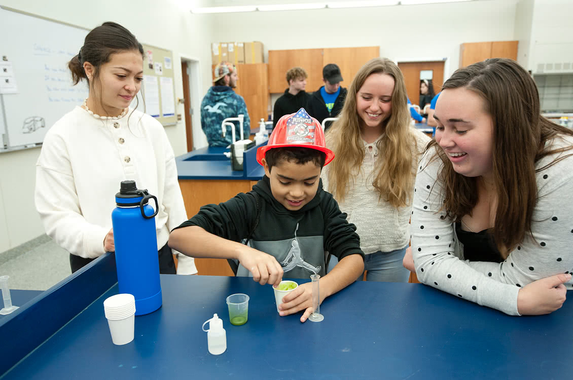 A group of women helping a child with an experiment