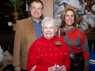 Three party attendees standing together, smiling