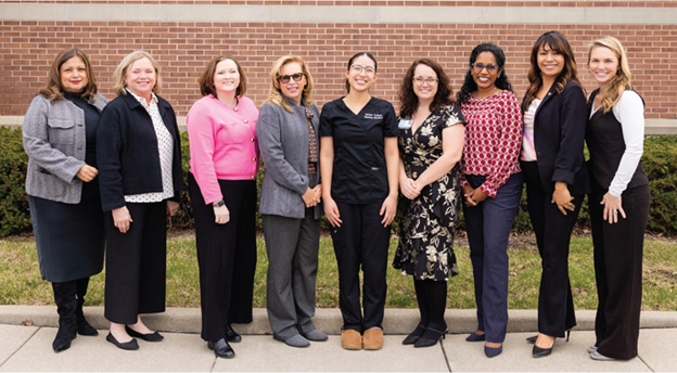 Representatives of Ascension Illinois smiling along with one of their scholarship recipients in front of a brick wall on the Harper College campus