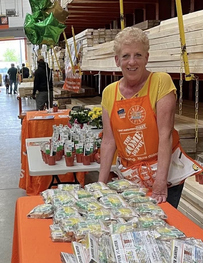Mary Boruta smiling, wearing a Home Depot apron behind a display table