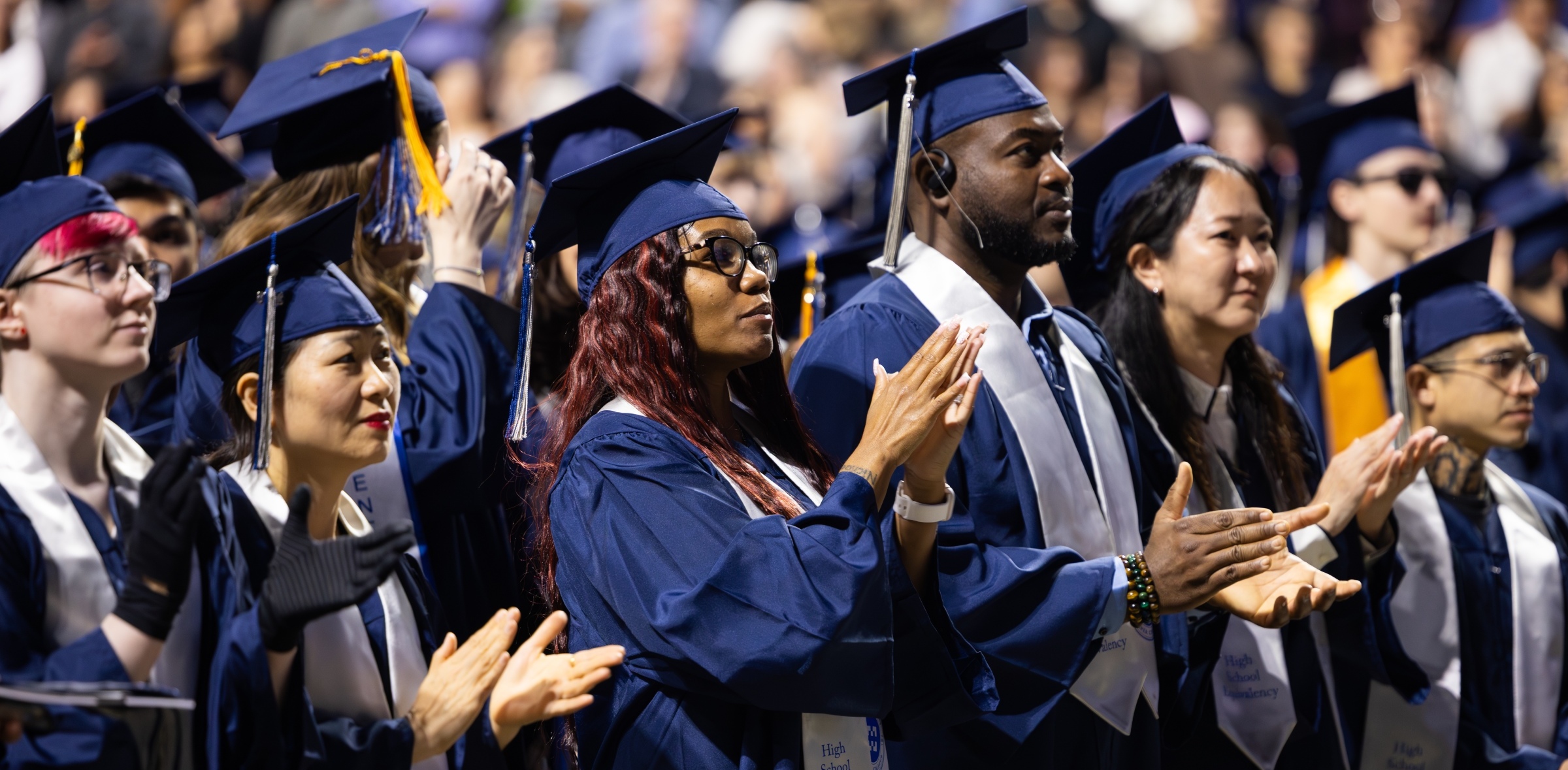 Harper graduates standing and clapping hands
