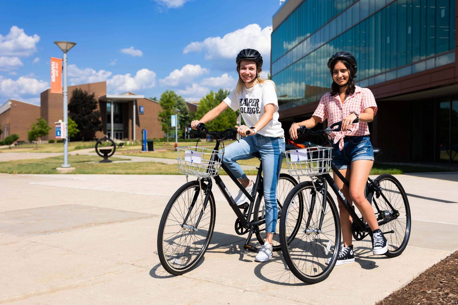 Two women riding bikes next to one another