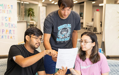 Students look over a sheet of paper together