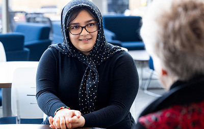 A female student in a head scarf meets with an admissions representative