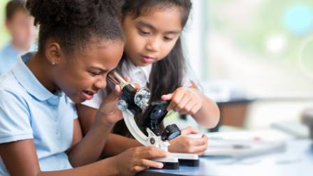 Two children looking into a microscope.