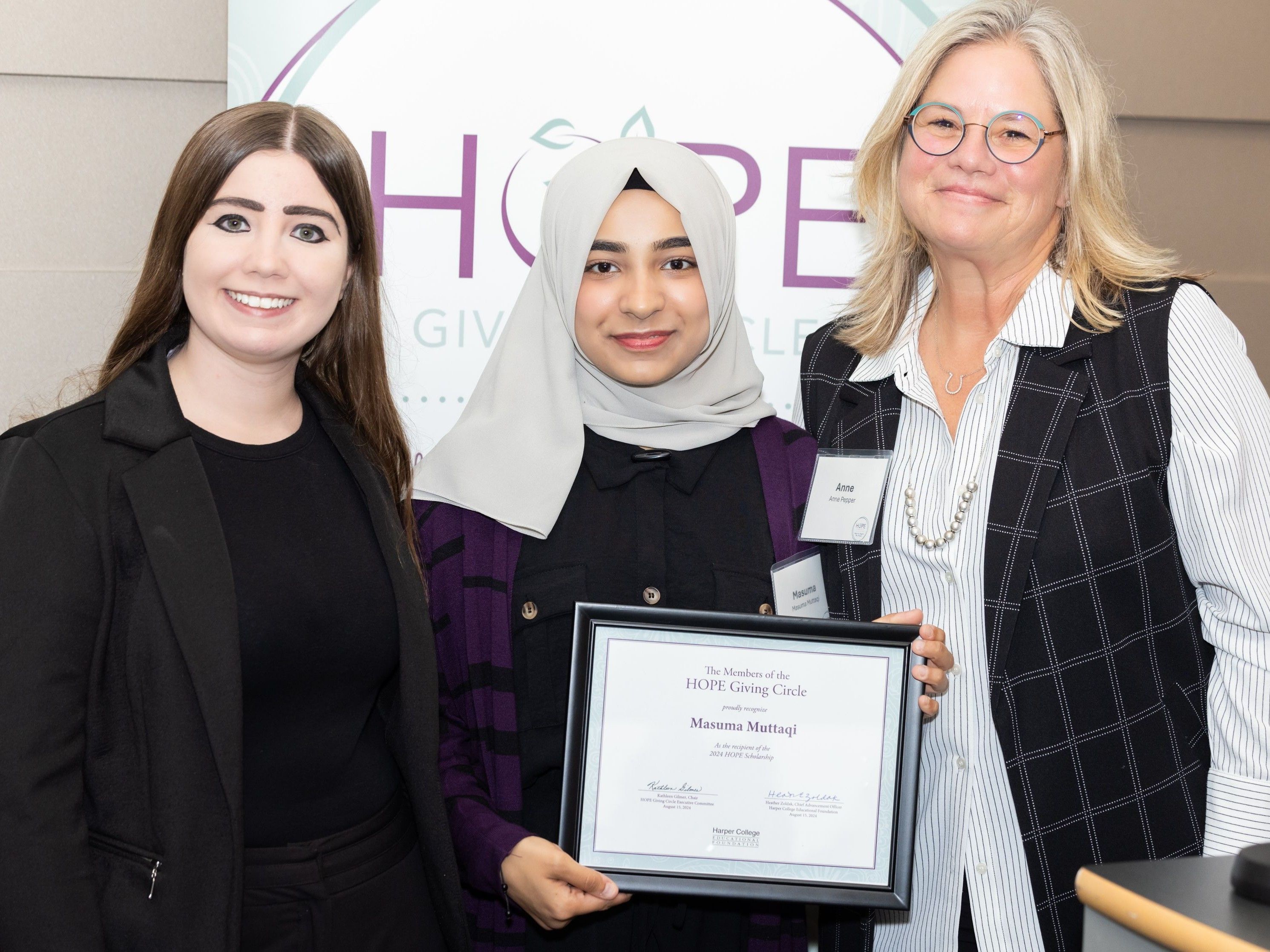 A HOPE member and a HOPE alumna stand on either side of a new HOPE scholarship recipient.