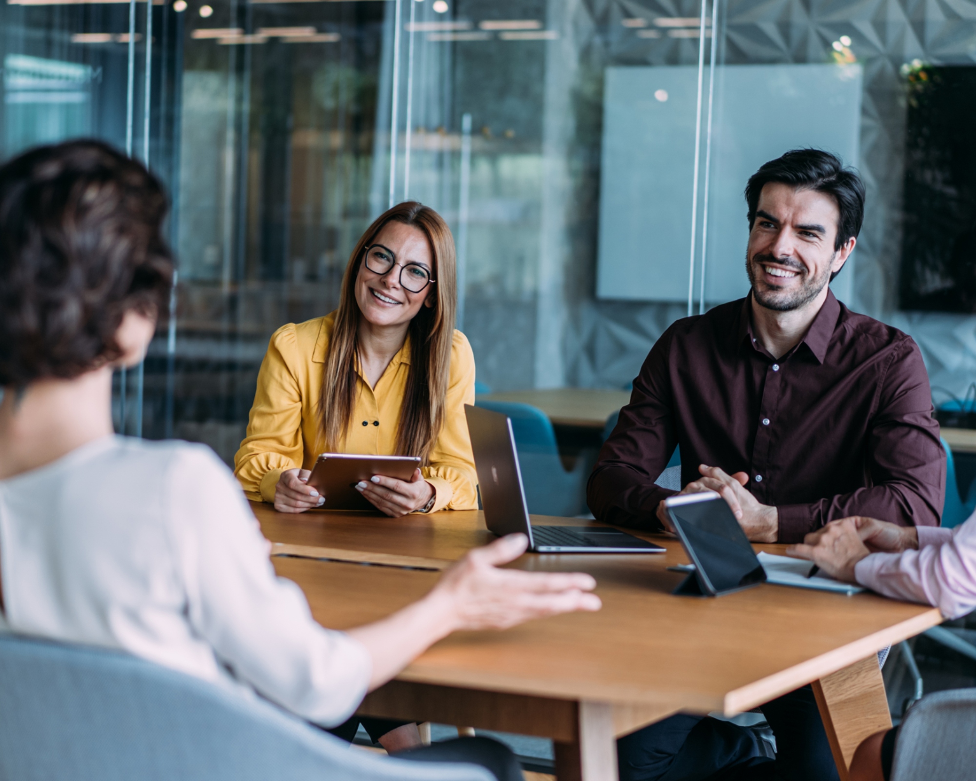 Cybersecurity professionals sit at a table for a meeting, engaged and listening to the ideas of another team member