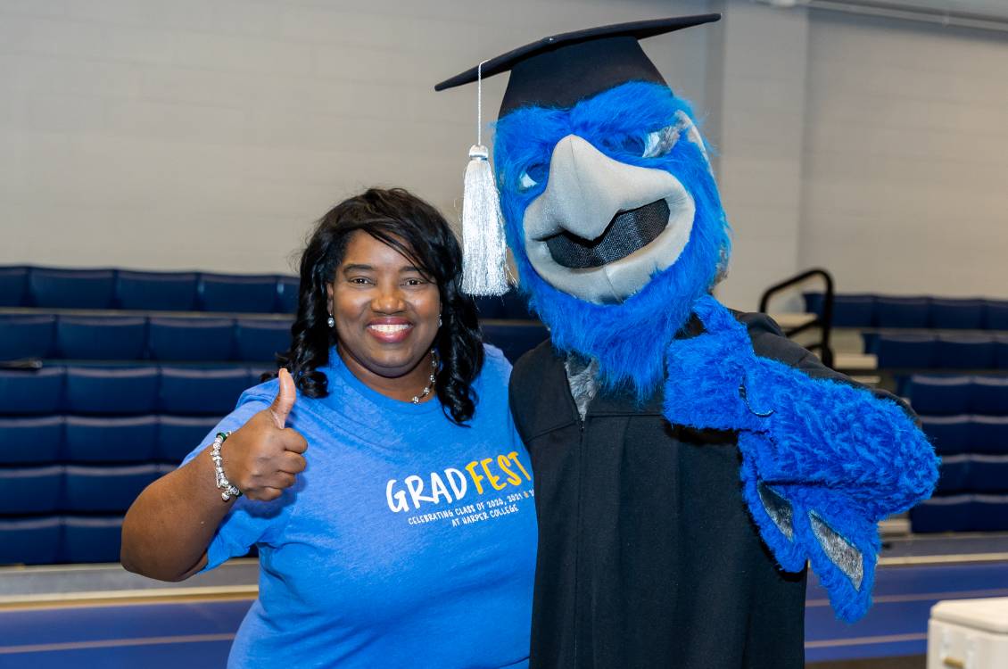 Dr. Proctor giving thumbs up with the Harper Hawk mascot at GradFest.