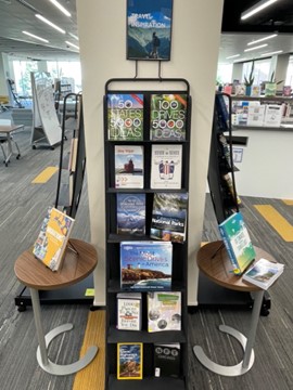 A picture of a library book display with recommendations for summer travel destinations.