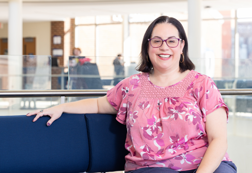 Carol Trejo Kroeger sitting on a couch and smiling
