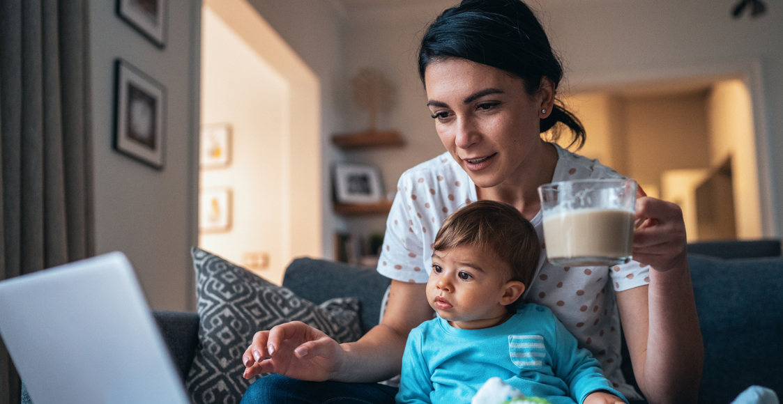 woman holding baby in lap and looking at laptop