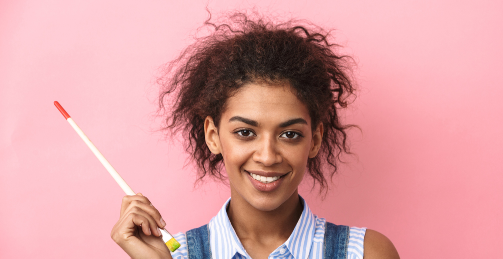 student smiling and holding paint brush