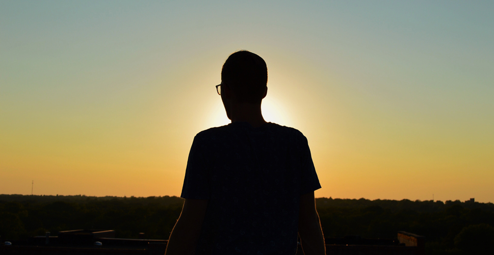 person standing silhouetted in the sunset