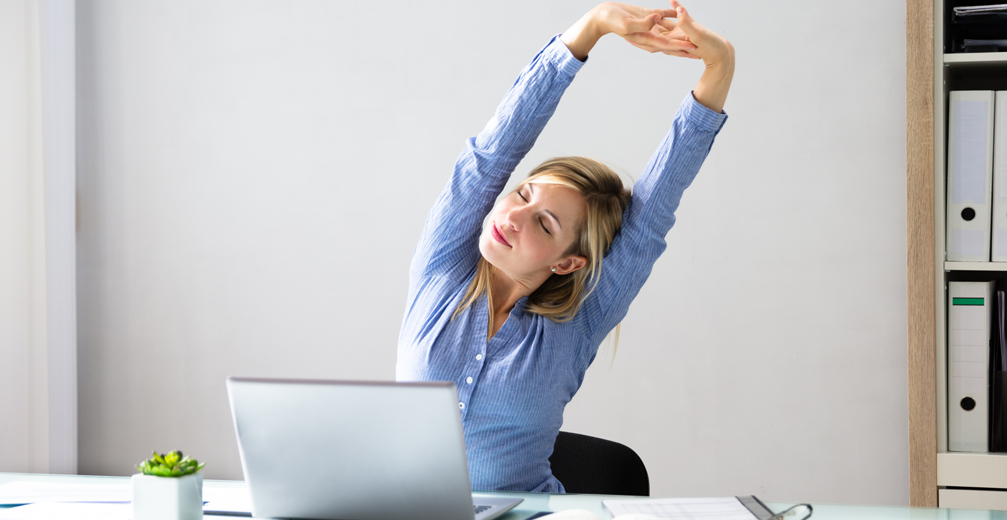 Woman sitting in front of computer stretching
