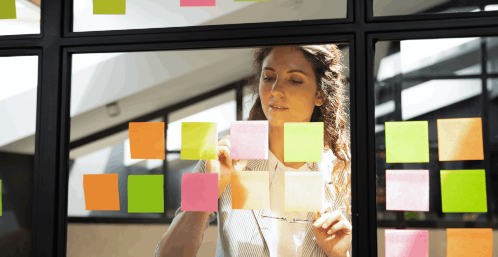 Woman arranging sticky notes on glass.