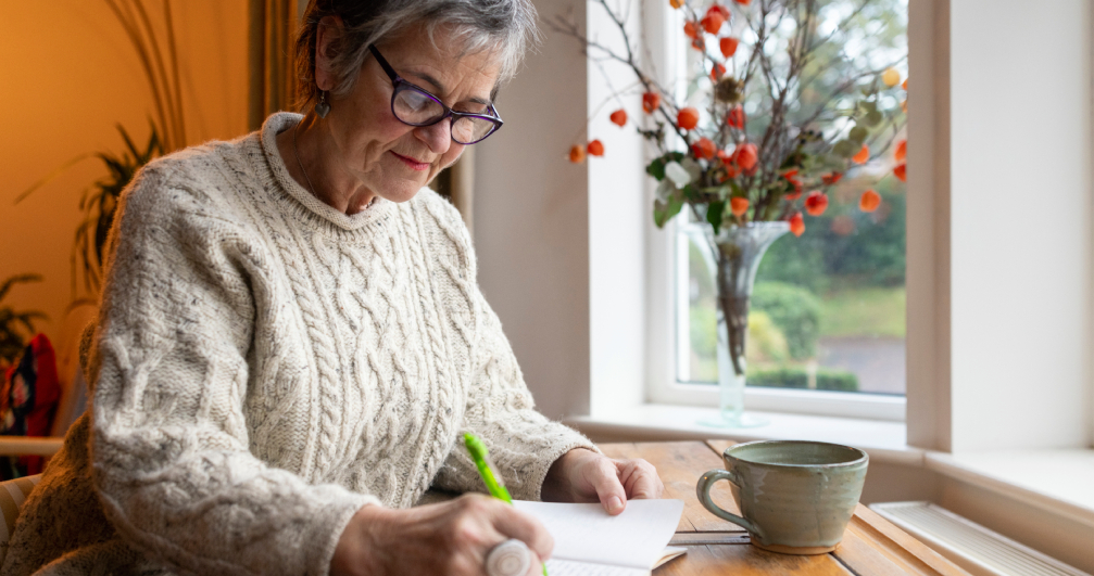 Woman writing in a gratitude journal. a woman sits by a window and writes in her journal