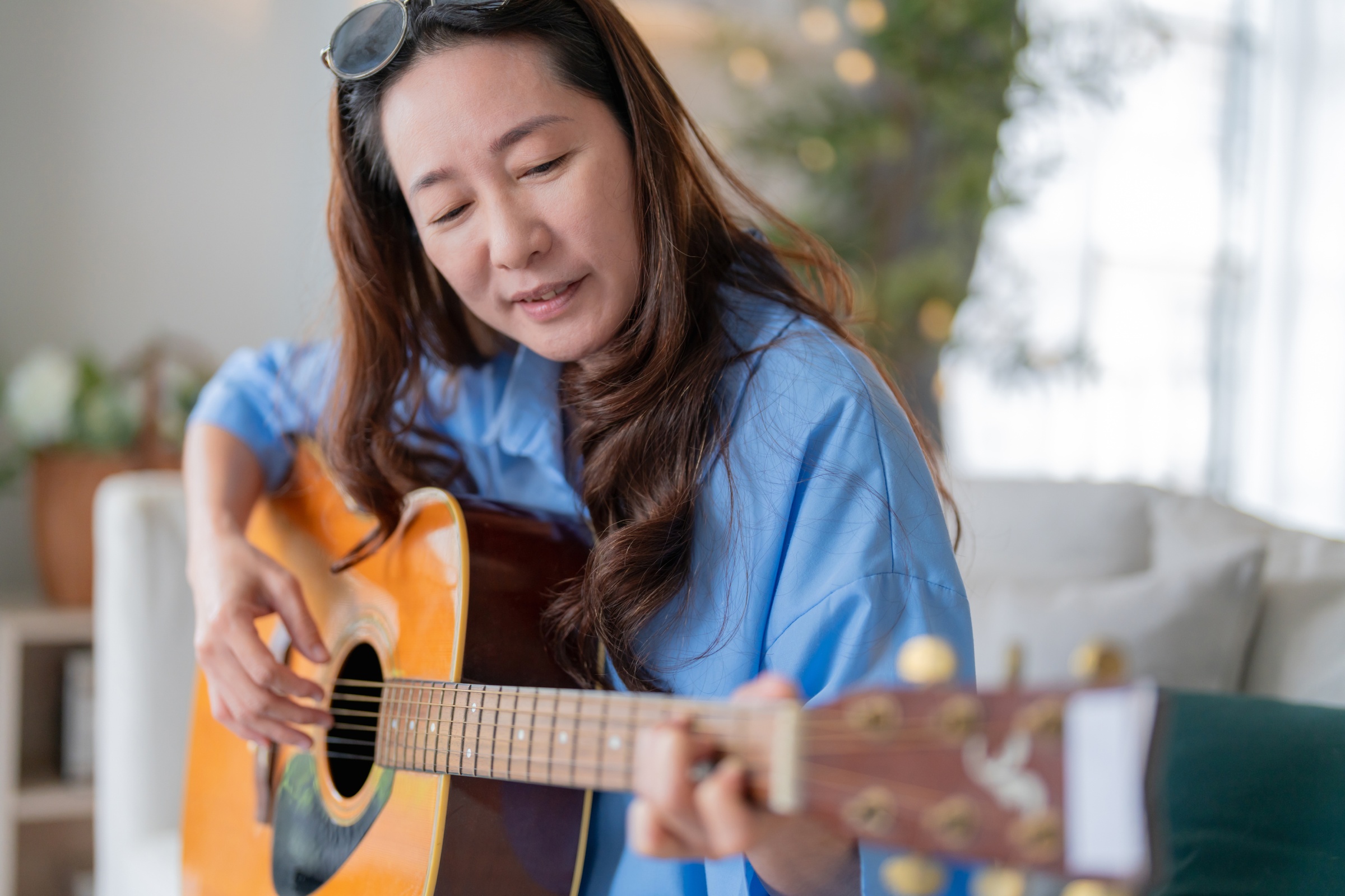 Woman learning how to play the acoustic guitar.