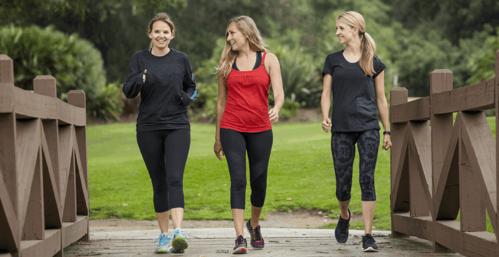 Three women walking on a wooden bridge