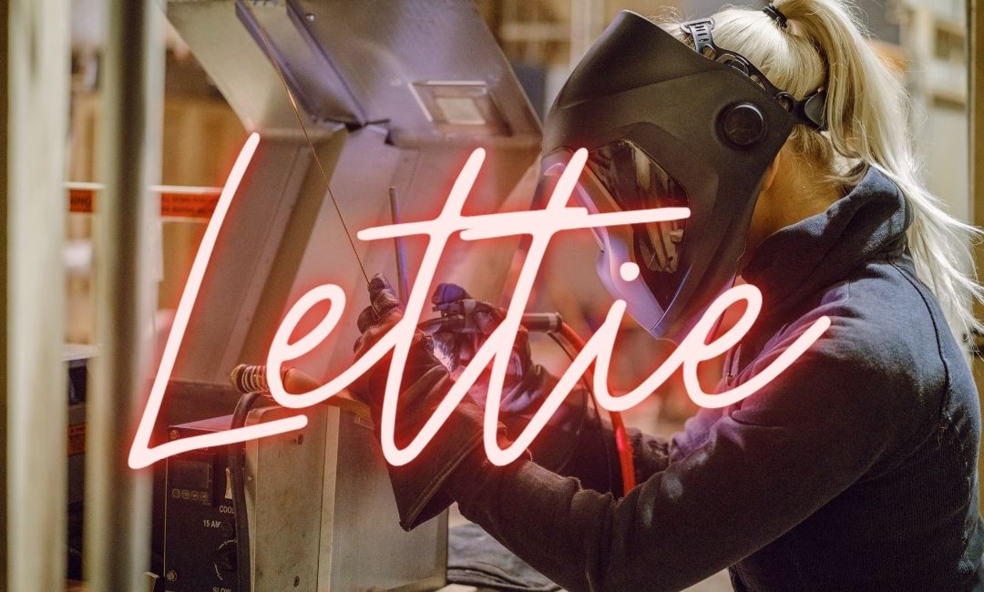 Lettie written in neon sign over an image of a woman in a welding mask working